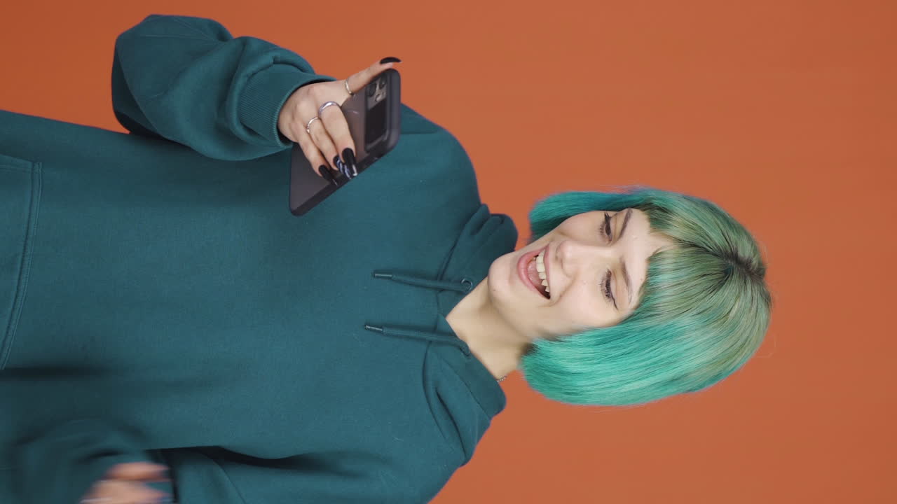el video vertical de la joven mirando el teléfono es feliz.