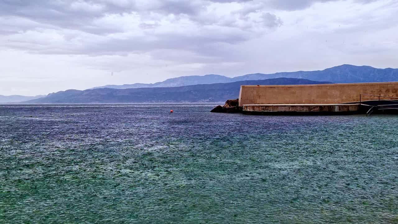 크로아티아 브라치 섬의 모래 해변에서 강한 비가 내린다.