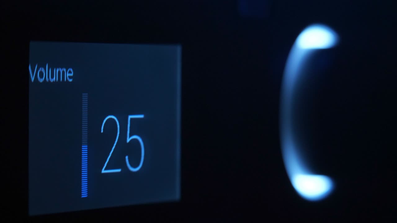 In the dark, the hand turns the volume control, illuminated by blue light