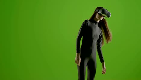 attractive girl young fashion model wearing a vr headset shot in green screen studio . interactive futuristic gesture . medium s