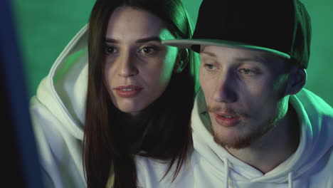 Portrait-of-modern-female-and-male-using-a-computer-on-a-neon-light-colorful-background.-Close-up.