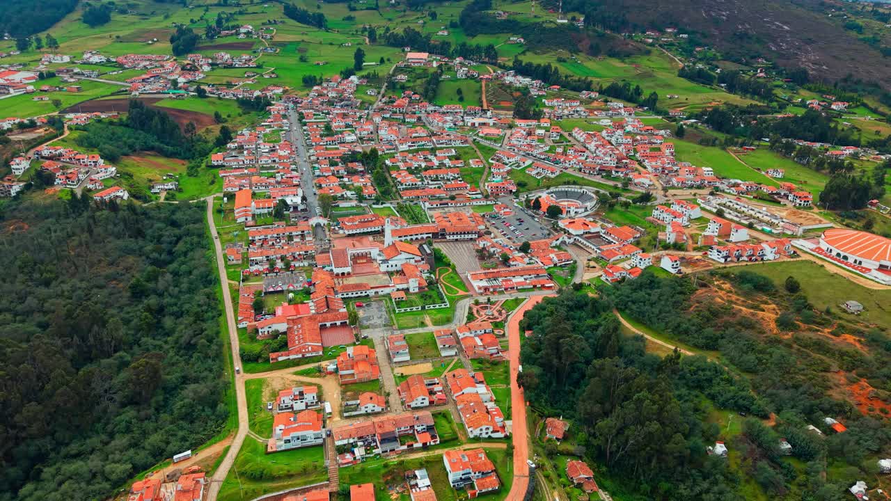 Aerial view dolly out revealing the tourist town of Guatavita with orange tile roofs in a natural environment near Bogota, Colombia.