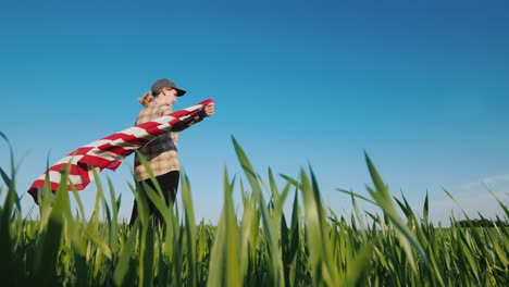 Una-Mujer-Sostiene-Una-Bandera-Estadounidense-En-Sus-Manos-De-Pie-En-Un-Prado