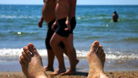 female feet sunbathing on the beach against the background of sand and blue sea with waves, womans bare feet on a beach