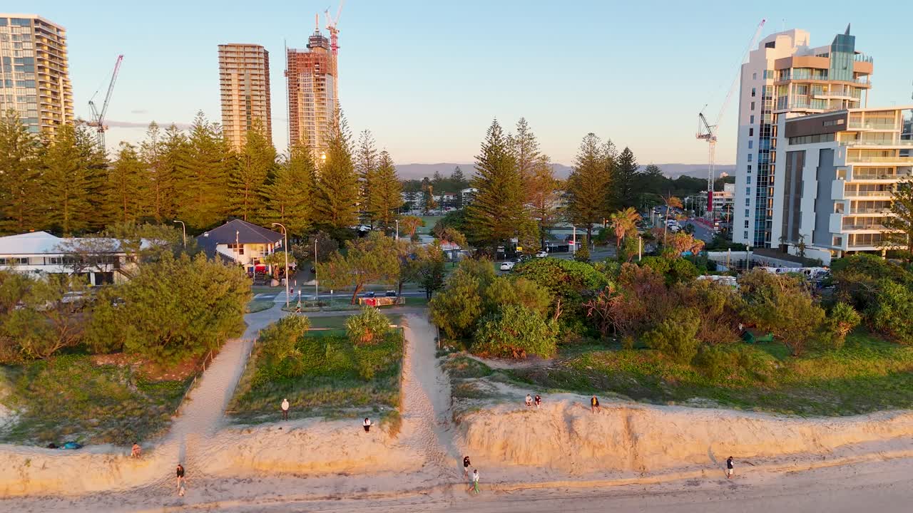 Drone captures serene morning at Gold Coast, highlighting beachfront, buildings, and lush greenery under soft sunrise lighting