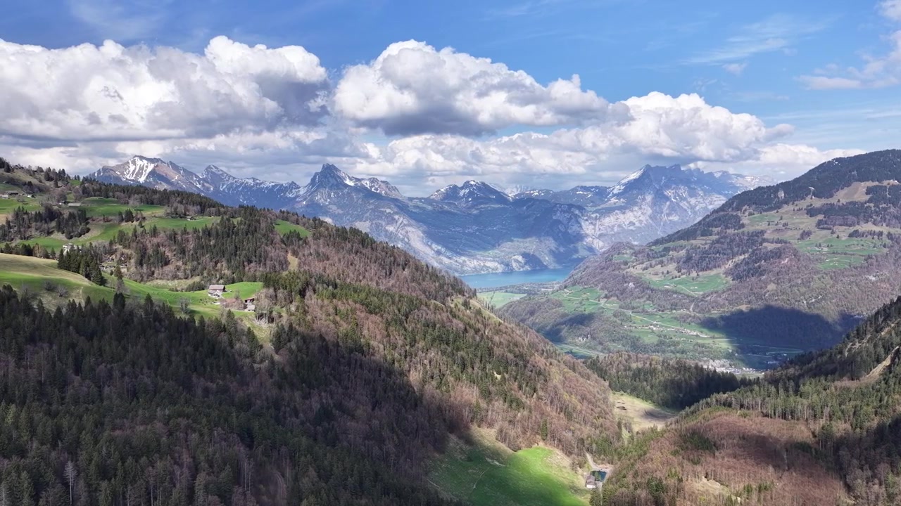 Riprese con drone che si affacciano su una pittoresca valle alpina con montagne imponenti e un lago in lontananza