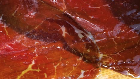 pouring olive oil on smoked red meat, close up view