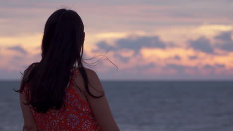 Mujer-Coreana-Solitaria-Y-Pensativa-Admirando-Una-Espectacular-Puesta-De-Sol-Ardiente-Con-Un-Cielo-Nublado-Y-Dramático-De-Vacaciones-En-Malasia---Vista-De-Perfil