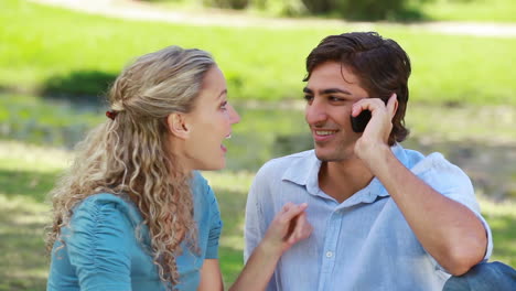 man talks on a phone as he passes the phone over to his girfriend