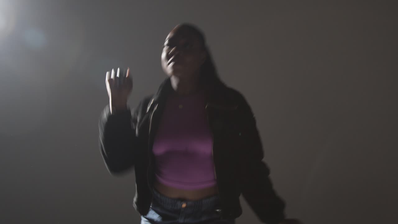 retrato de estudio de una mujer joven bailando con iluminación baja contra un fondo gris 12