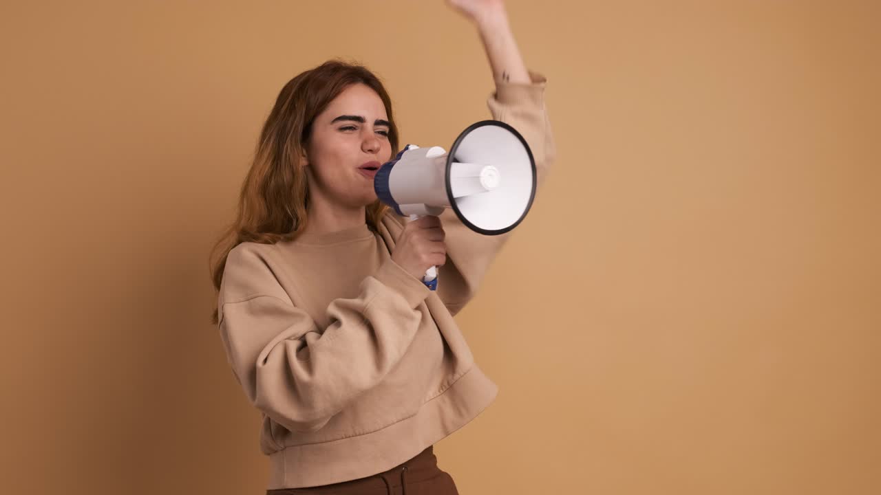 Young woman shouting into loudspeaker with hand gesture