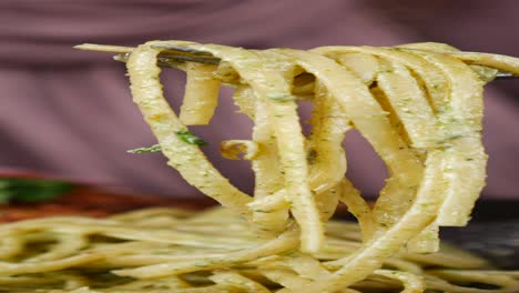 close up of a fork with a strand of spaghetti covered in pesto