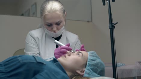 skilled woman applies permanent make-up in beauty salon