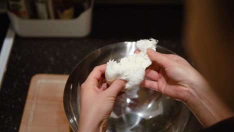 una mujer chef rompiendo la bola de mozzarella en pedazos más pequeños