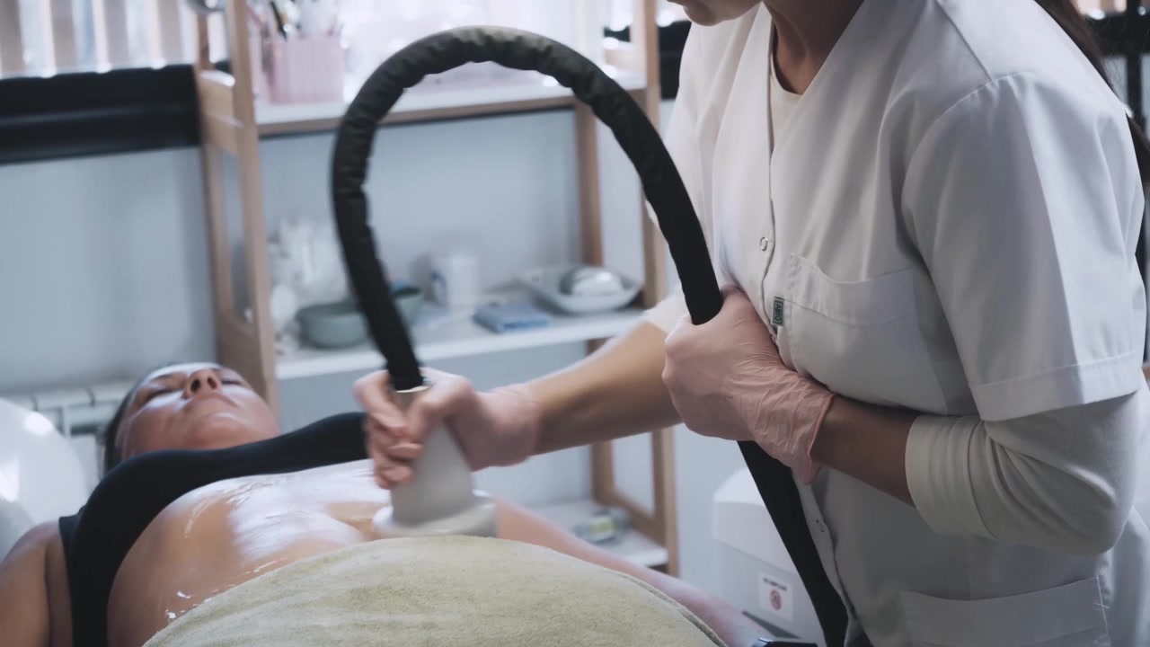 Cosmetologo/a che esegue trattamento di cavitazione addominale su cliente