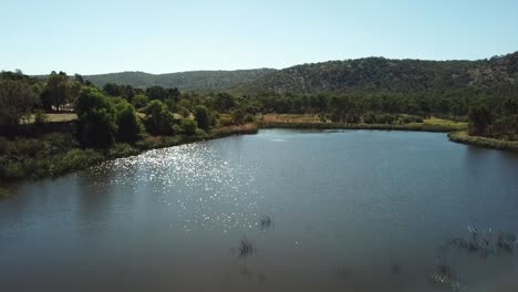 AERIAL:-Drone-shot-moving-over-a-lake-rising-higher-to-reveal-El-Dorado,-a-regional-gold-mining-village-in-Victoria,-Australia