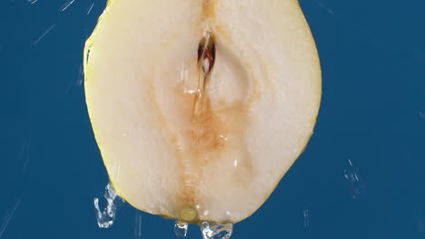 detail of pear slice with water falling on the piece in slow motion