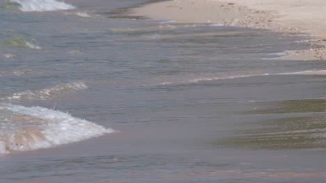 Mittlere-Nahaufnahme-Des-Weißen-Sandstrandes-Mit-Dem-Ozean,-Der-Sanft-Auf-Den-Sand-Plätschert