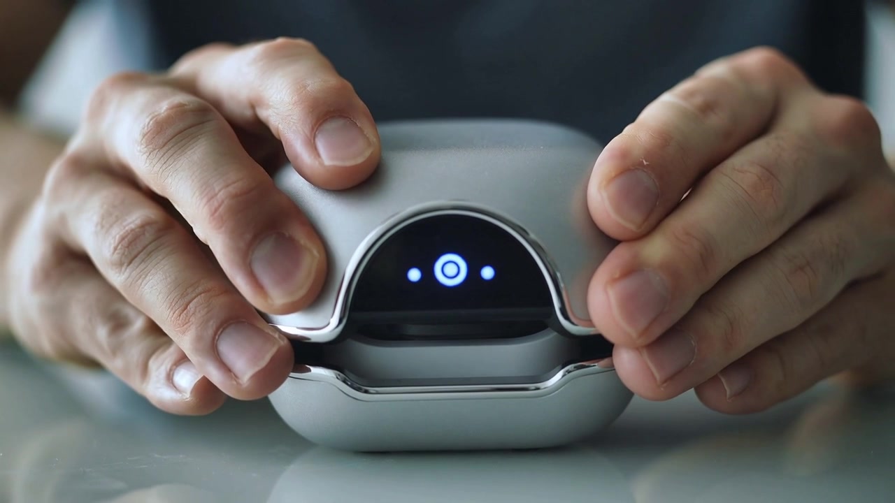 Seeing LED glow, male-presenting hands lowering and aligning metallic case on desk for charging