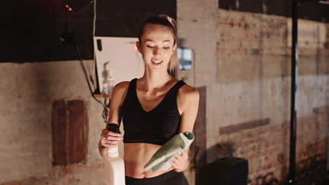 Zeitlupe-Der-Lächelnden-Jungen-Frau,-Die-Im-Fitnessstudio-Wasser-Auf-Tuch-Sprüht