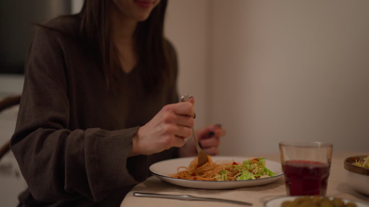 Woman eating spaghetti at a table