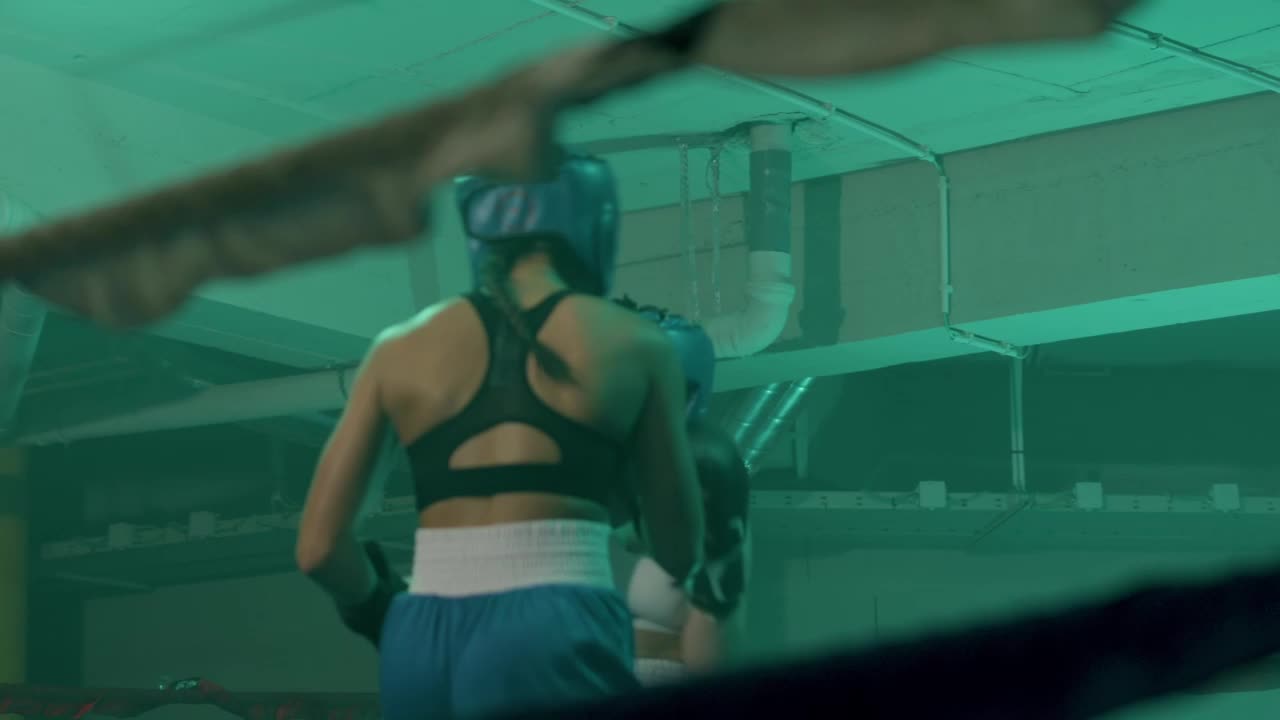 체육관에서 링에서 싸우는 헬멧과 권투 장갑에 두 명의 여성 권투 선수