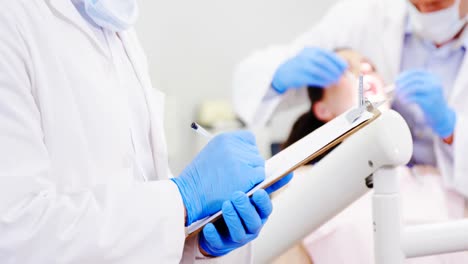 el dentista escribe detalles en el clipboard.