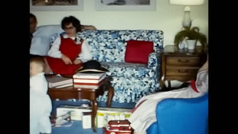 little boy and girl sitting on blue chair together. circa usa - 1970s: a 1970s archival photo capturing a little boy and girl sitting side by side on a blue chair in the usa.