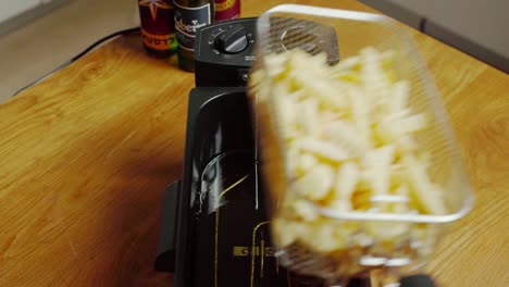 hands opening lid of deep fryer, putting in basket of fries