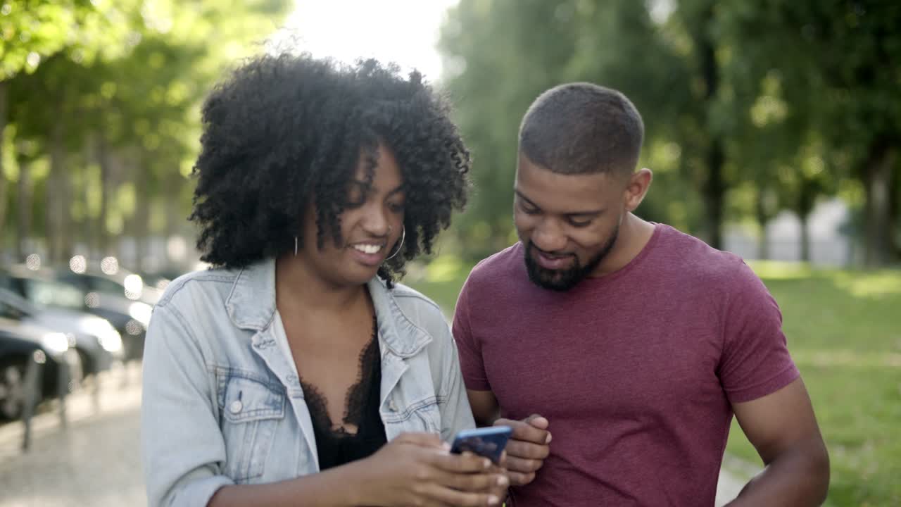 feliz pareja afroamericana mirando el teléfono inteligente