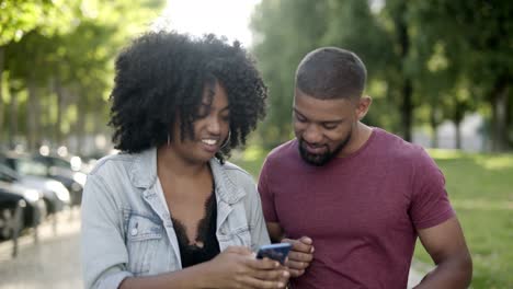 Glückliches-Afroamerikanisches-Paar,-Das-Auf-Das-Smartphone-Schaut