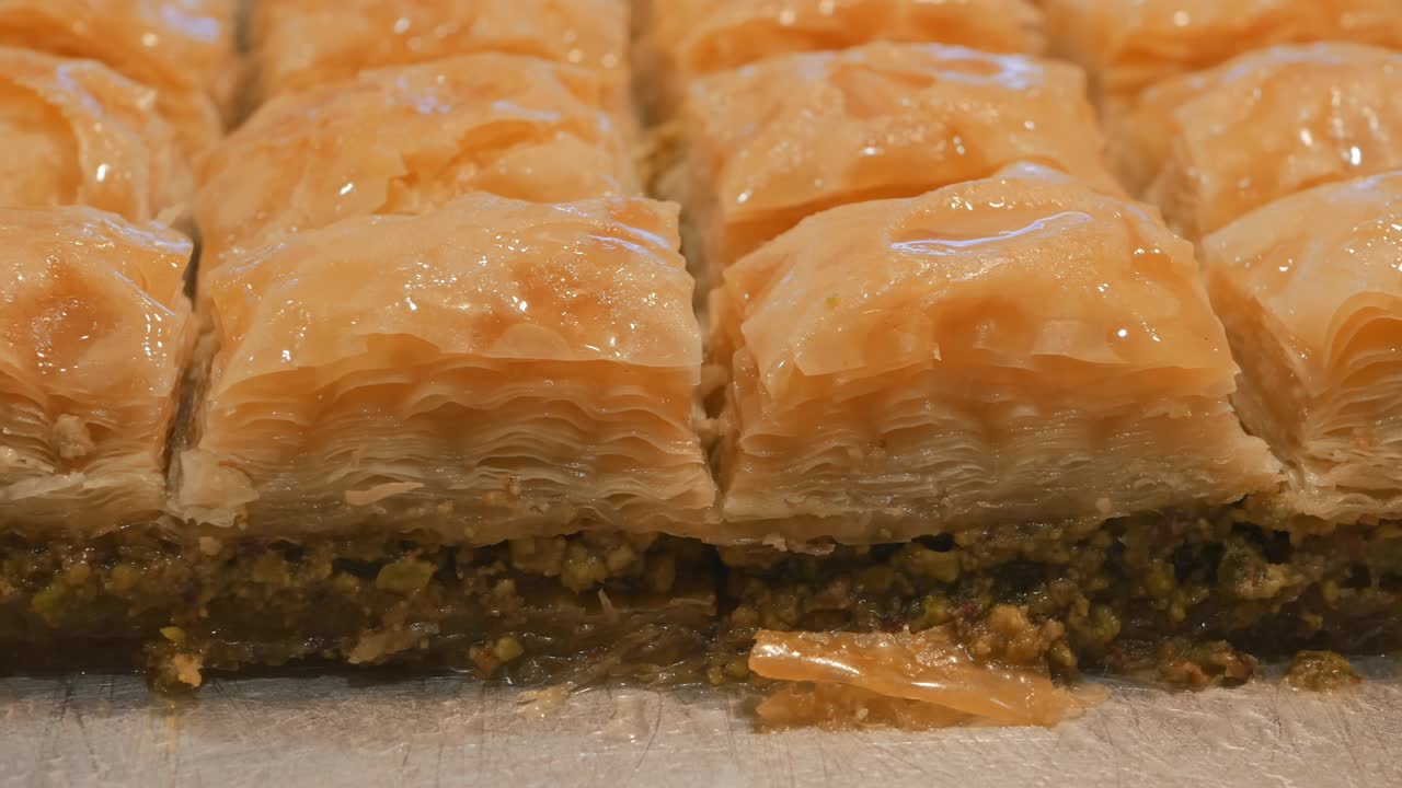 Klassinen turkkilainen baklava pistaasitäytteellä makeassa siirapissa. Dolly-kuvaus makeisista. 4k-kuva. Lähikuva.