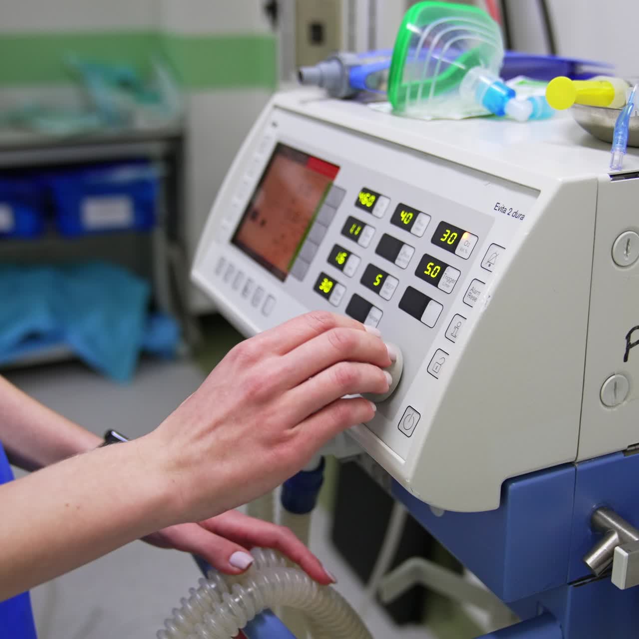 Medic in blue uniform setting parameters on the equipment in operational room. Tools and instruments are on the apparatus. Close up. Blurred backdrop