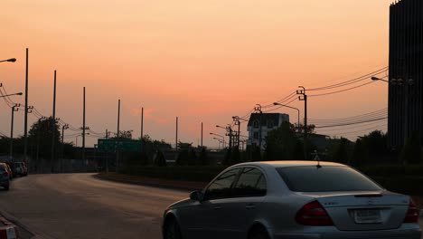 vehicles move as the sun sets in a vibrant sky