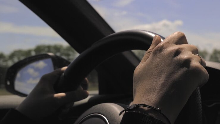 Gros plan des mains d'une femme et du volant pendant qu'elle conduit