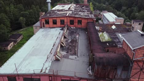 drone flies closely over the roof of an lost place in the middle of saxony a view on a former socialist veb brick factory in the evening light