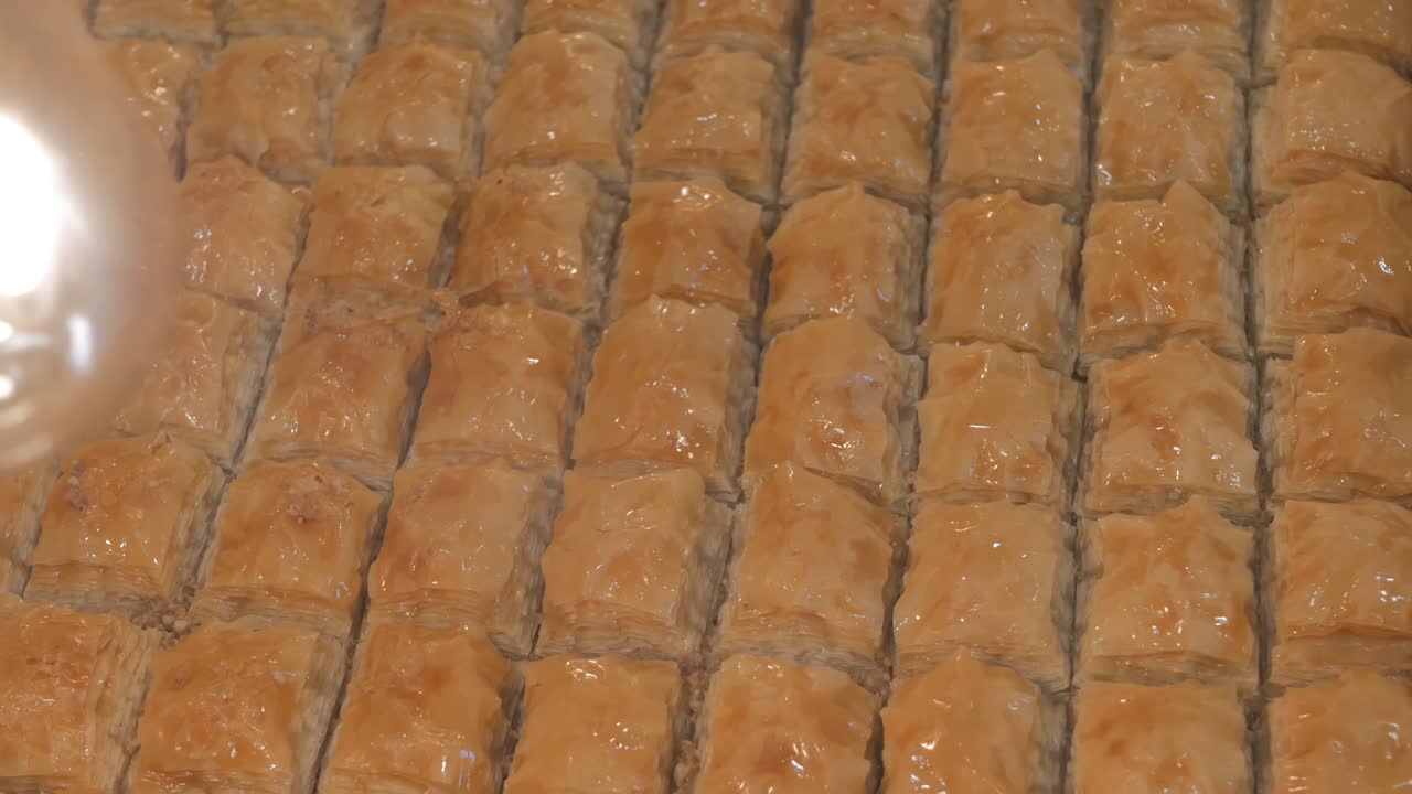 Turkkilaista baklavaa leivinpellillä kaupan ikkunassa. Dolly-kuvaus, ylhäältäpäin. Luonnollisia turkkilaisia makeisia.