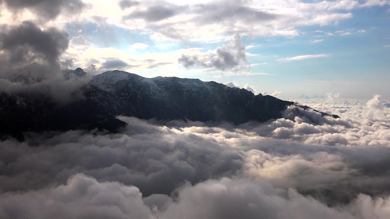Vue aérienne d'une majestueuse chaîne de montagnes au-dessus d'une mer de nuages.