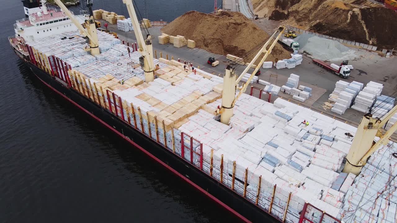 Busy industrial port with large cargo vessel, active loading operations, drone