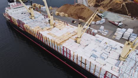 Busy industrial port with large cargo vessel, active loading operations, drone