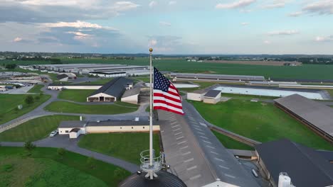 American-flag-waving-over-large-farm-in-rural-USA-during-summer