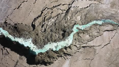 dead sea hot springs aerial top down shot fast zoom in over desert canyon landscape with crystal clear aqua colored warm waters