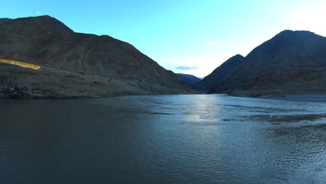 the confluence and convergence of river zanskar and indus with mountains and sun in the background flow of pure water from mountains