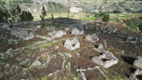 aerial descends to old stone buildings: uyo uyo archeology site, peru