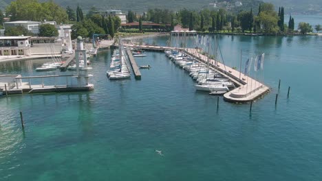 Beautiful-drone-shot-of-the-marina-in-Riva-Del-Garda-with-white-sailing-boats-on-the-lake-garda-on-a-sunny-day