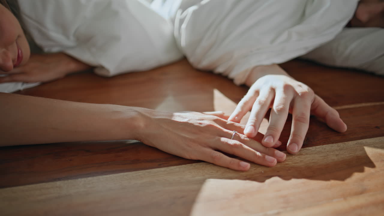 Closeup loving hands connecting in sunlight. Serene couple enjoying intimate