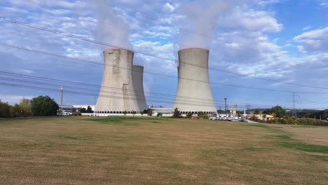 aerial forward shot of nuclear power plant cooling towers and high voltage line