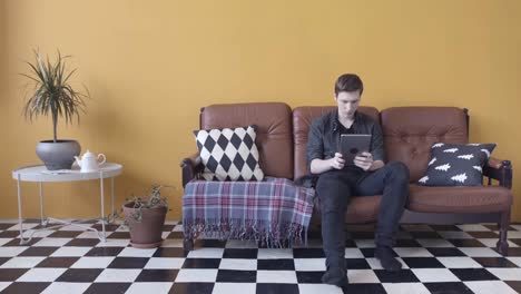 man relaxing on sofa with tablet