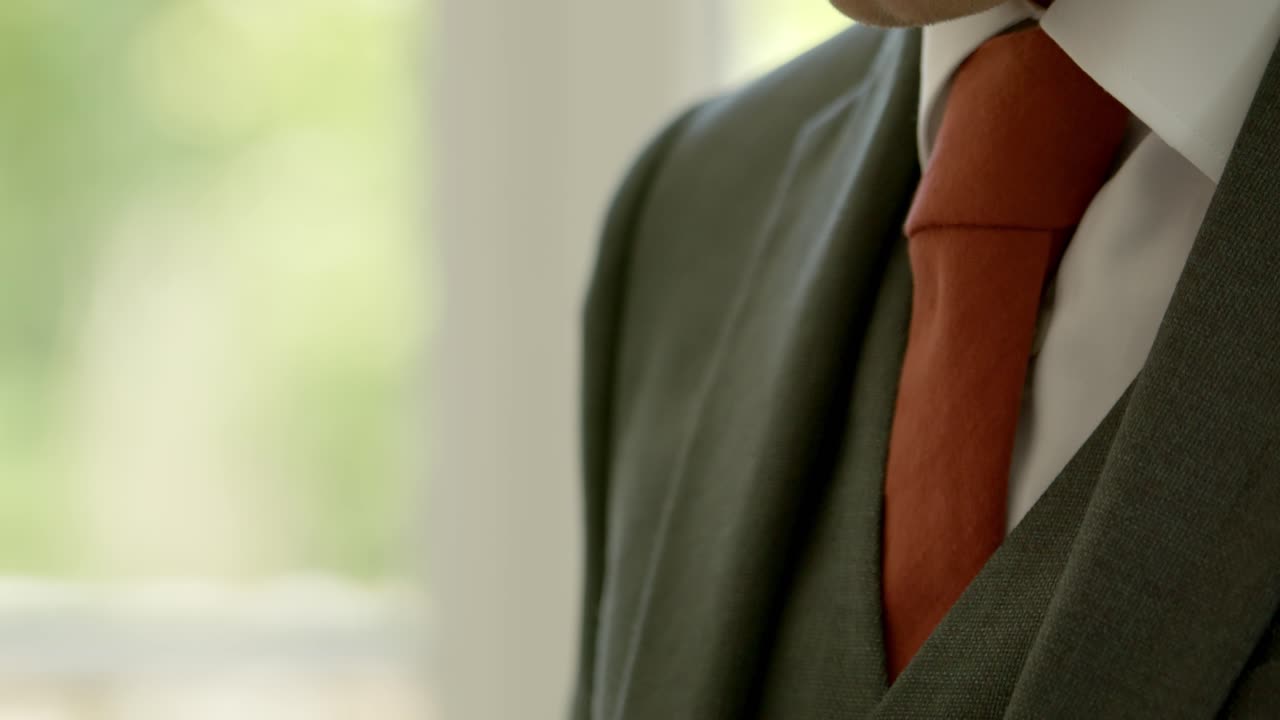 Father adjusting groom's tie before wedding, close up view