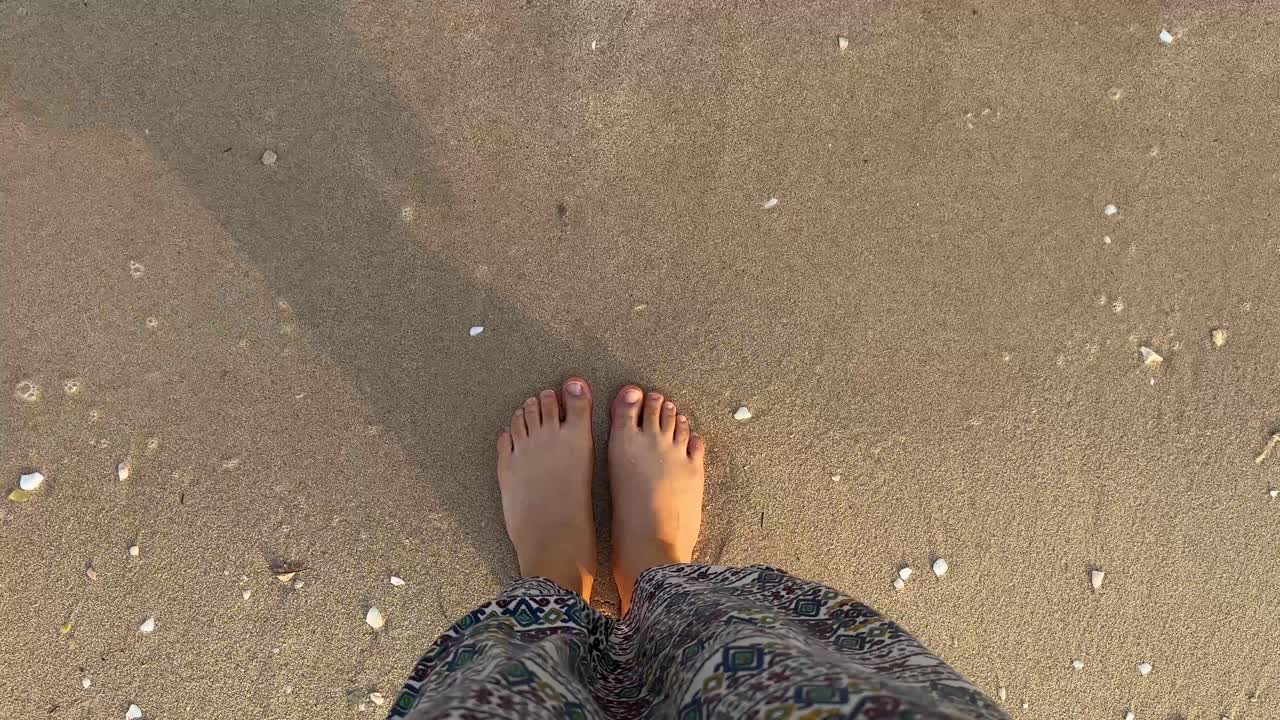 piernas y pies femeninos delgados se paran a lo largo de las olas de agua de mar en la playa de arena en doha qatar